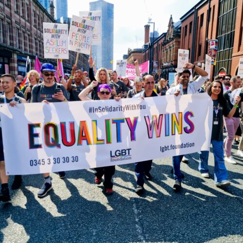 A large group of people marching on a parade with a banner reading 'Equality Wins' to show support for asylum seekers.