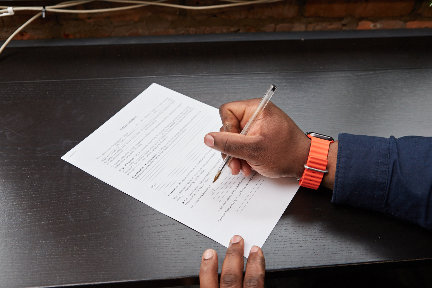 Black person writing answers to questions on a piece of paper. Focus on hand.
