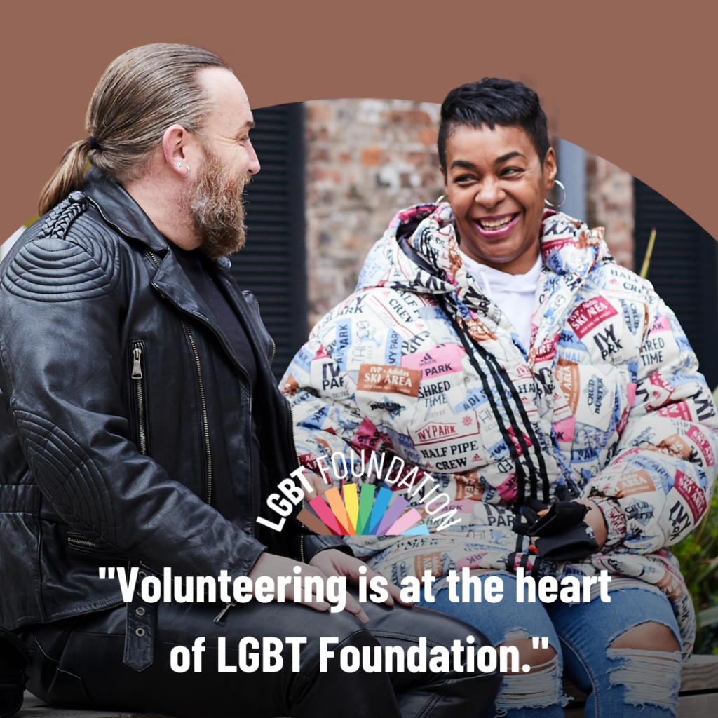 a queer black woman speaks with a gay man sat wearing leather, they are both laughing together. The text overlay reads: volunteering is at the heart of LGBT Foundation"