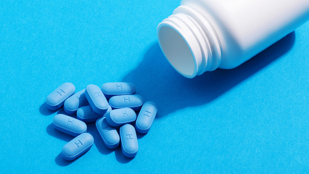 A handful of blue PEP pills spilt on the side of a medicine bottle.