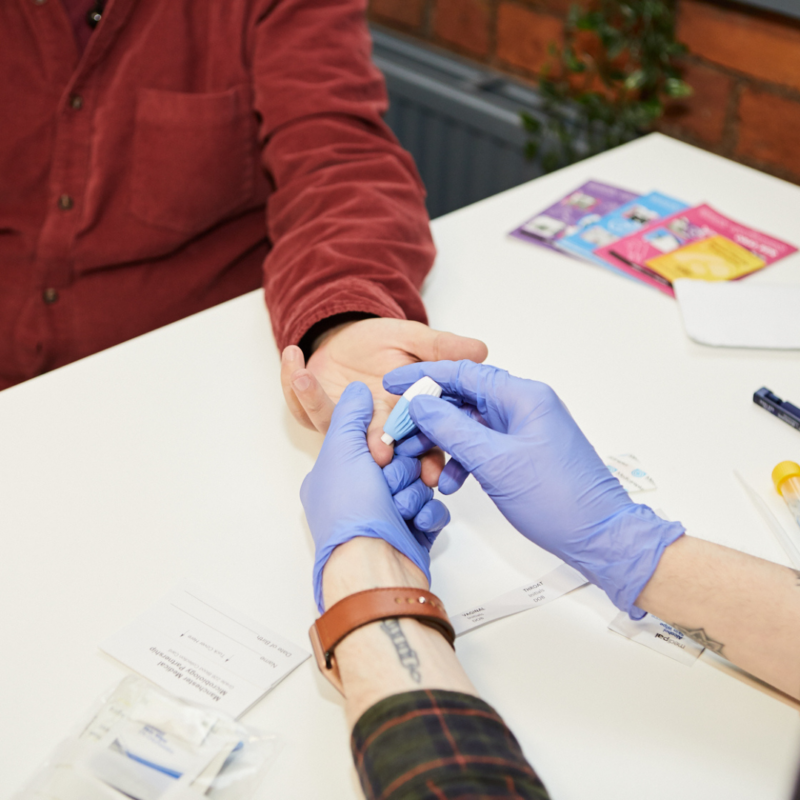 A service user getting their finger pricked, testing for STIs and HIV.