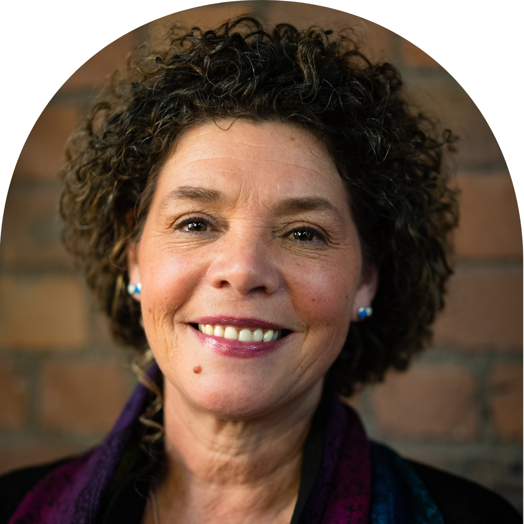 Older lesbian woman of colour with short curly hair smiling at camera. Portrait.