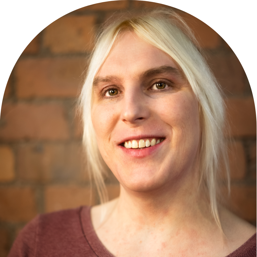 Trans woman with blonde hair smiling at camera. Portrait.