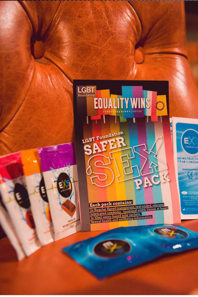 Close-up to condoms, lube and the Safer Sex Pack on a leather chair.