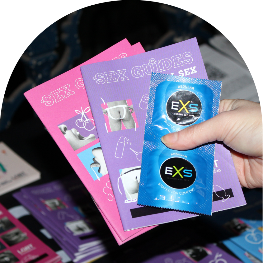 Person holding condoms and LGBT foundation sex guides. Close-up on the items.