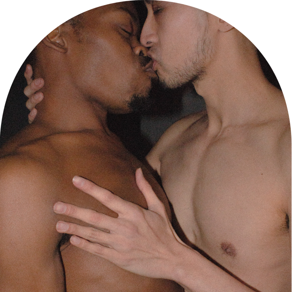 A black and an Asian man holding each other and kissing. Close-up shot.