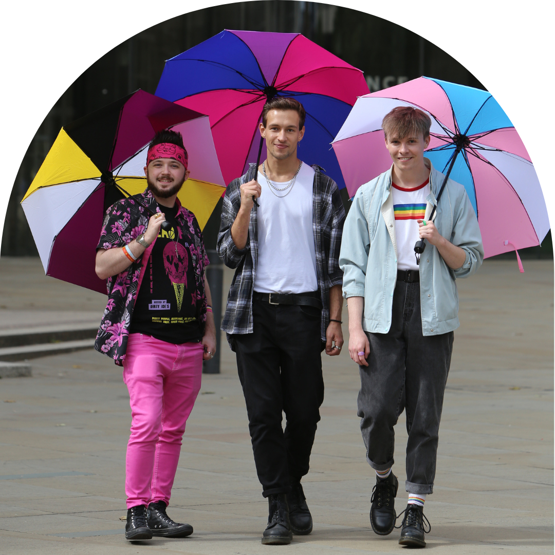 Three men walking towards camera, smiling. Each holding an umbrella resembling non-binary, bisexual and trans flags.