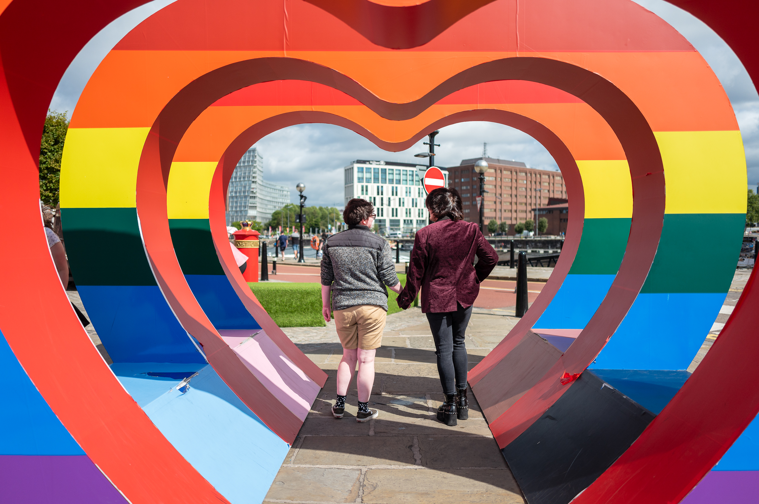 Two people viewed from the back inside a row of rainbow hearts in Liverpool City Centre