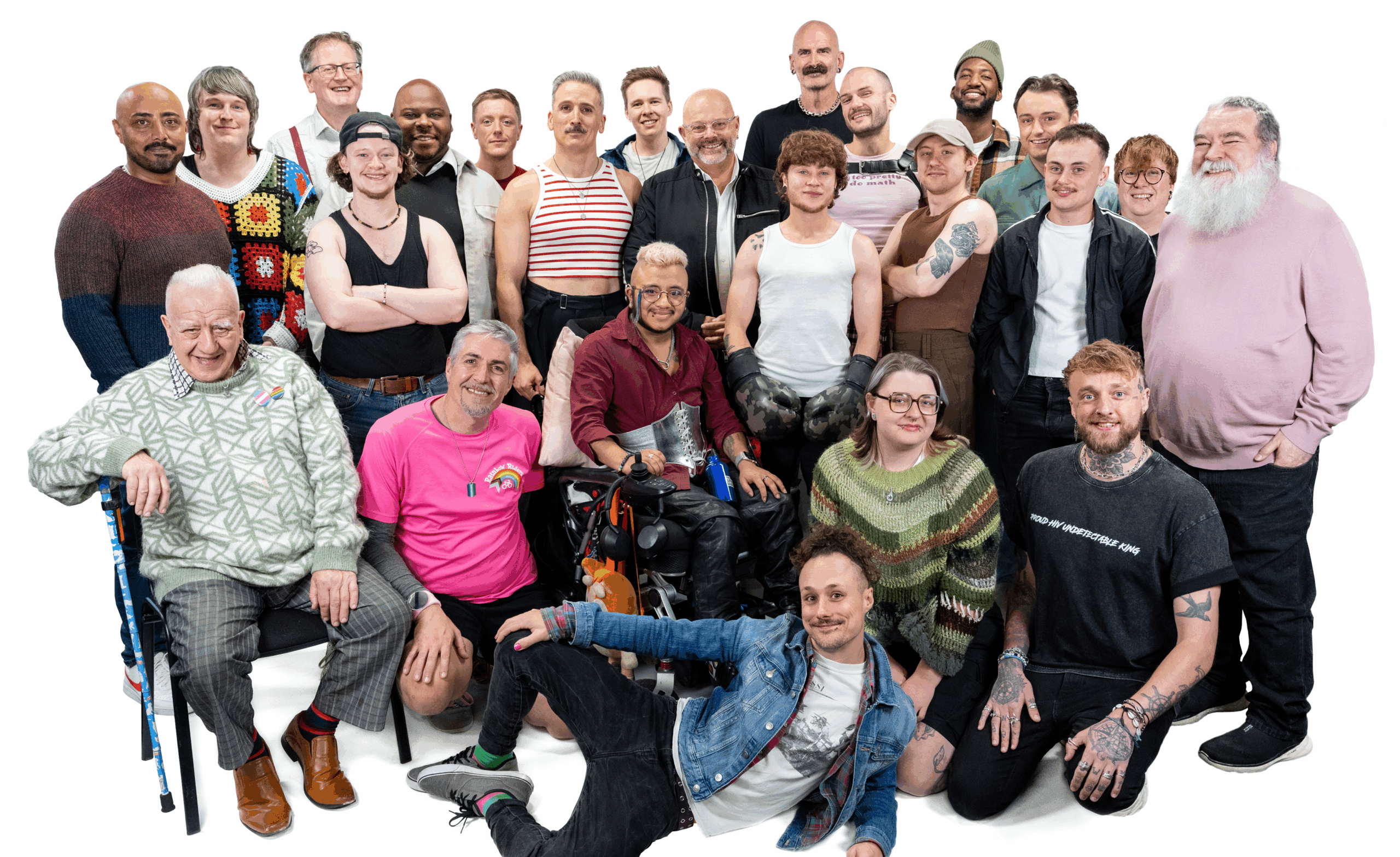 A large group of LGBTQ+ men smiling and looking at the camera against a white backdrop for LGBT Foundation's Man Enough campaign